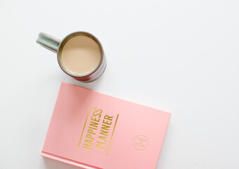 Pink and gold glamourous planner with a green cup of hot coffee for new years resolutions