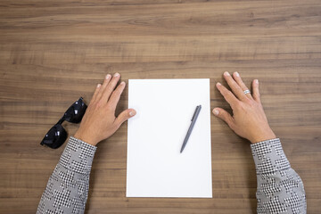 Obraz premium man's hand signing document, white paper with black and gold pen, wooden background.