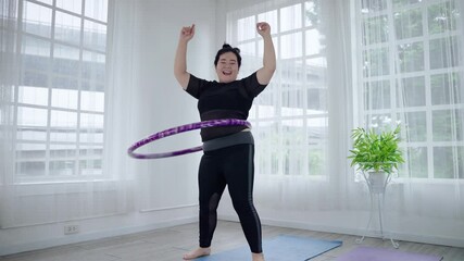 Fat Asian woman playing hula hoop to lose weight cheerfully in her room. health and weight loss concept - Powered by Adobe