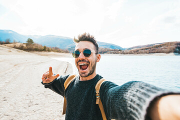 Handsome man with backpack taking selfie outdoor - Young hiker travel on mountains smiling at...