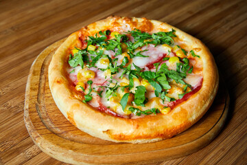 Pizza with cheese, bacon and herbs on a wooden plate. Close-up, selective focus