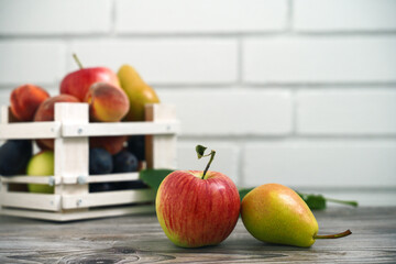 apple and pear on a white brick wall and a wooden box with freshly washed fruit. free space for inscription