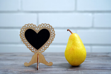 ripe pear and wooden heart with copy space on the table. concept of love eating pears and healthy food.