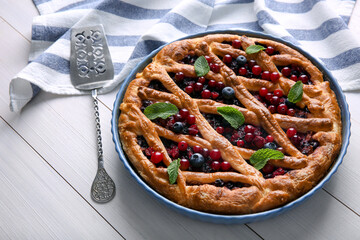 Delicious currant pie and fresh berries on white wooden table