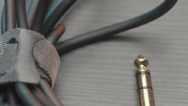 Close up of an acoustic cable lying on wooden table surface. Action. Rolled audio jack cable, details of professional equipment.