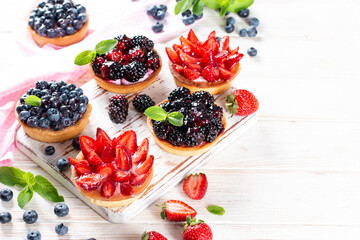 Freshly baked mini tarts with berries on a table. Summer fruit baking. Copy space. Top view.