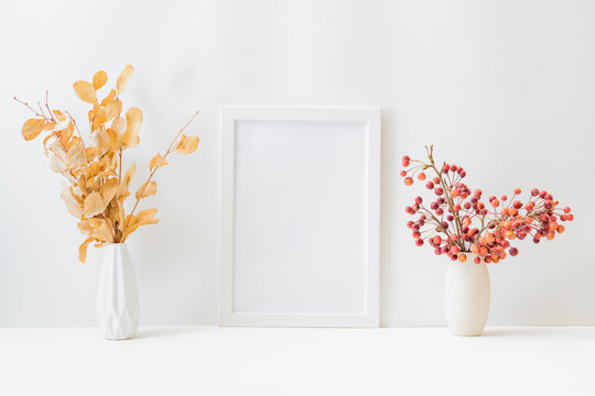 Home interior with decor elements. Mockup with a white frame, Dry autumn leaves in a vase on a light background