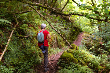 old woman with gray hair hiking in the woods.