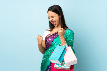 Young Indian woman with shopping bags celebrating a victory