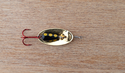 Simple black and yellow spoon fishing lure with a red treble hook.