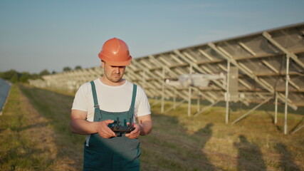 An employee of a solar power plant talks on a walkie-talkie while his colleagues and an investor...