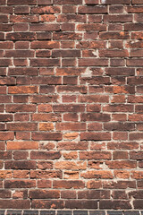 Brick old wall of dark red color. Vertical vintage background. Exterior.