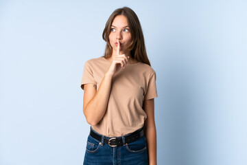 Young Lithuanian woman isolated on blue background showing a sign of silence gesture putting finger...