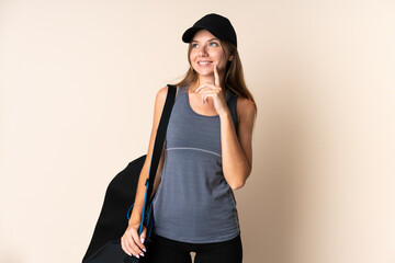 Young sport Lithuanian woman holding a sport bag isolated on beige background thinking an idea while looking up