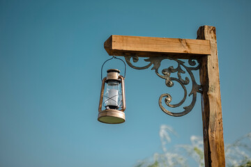 Outdoor low angle view of antique lantern with blue sky background hanging on a pole