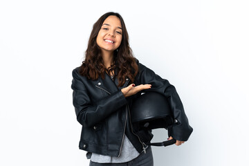 Fototapeta premium Young woman holding a motorcycle helmet over isolated white background presenting an idea while looking smiling towards