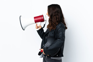 Young woman holding a motorcycle helmet over isolated white background shouting through a megaphone