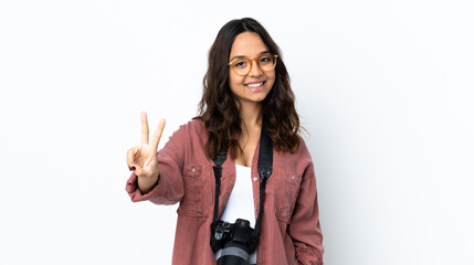 Young photographer woman over isolated white background smiling and showing victory sign