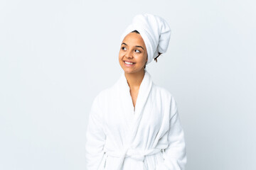 Young woman in bathrobe over isolated white background thinking an idea while looking up