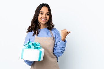Pastry chef holding a big cake over isolated white background pointing to the side to present a product