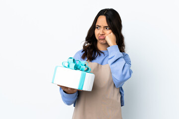 Pastry chef holding a big cake over isolated white background with tired and bored expression