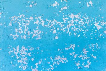 Blue flakes of old peeled dirty paint from the surface of the white concrete wall texture background