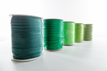 rolls with green decorative ribbons of different shades for clothes on a white background