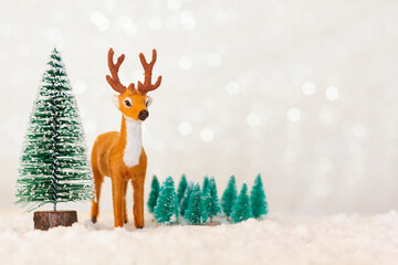 Reindeer and pine trees on snowy background with copy space