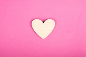 wooden heart on pink background, valentines day love symbol.