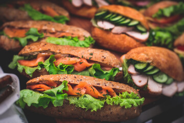 Beautifully decorated catering banquet table with different food snacks and appetizers setting with sandwiches, triange, croissant club submarine sandwich, on a wooden plate, on party or celebration