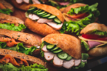 Beautifully decorated catering banquet table with different food snacks and appetizers setting with sandwiches, triange, croissant club submarine sandwich, on a wooden plate, on party or celebration