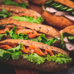 Beautifully decorated catering banquet table with different food snacks and appetizers setting with sandwiches, triange, croissant club submarine sandwich, on a wooden plate, on party or celebration