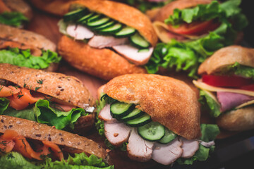 Beautifully decorated catering banquet table with different food snacks and appetizers setting with sandwiches, triange, croissant club submarine sandwich, on a wooden plate, on party or celebration