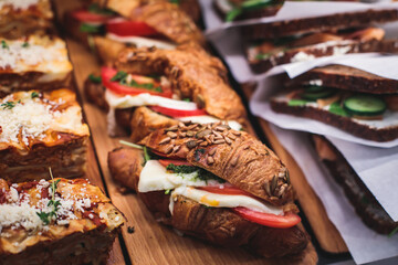 Beautifully decorated catering banquet table with different food snacks and appetizers setting with sandwiches, triange, croissant club submarine sandwich, on a wooden plate, on party or celebration