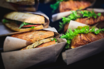 Beautifully decorated catering banquet table with different food snacks and appetizers setting with sandwiches, triange, croissant club submarine sandwich, on a wooden plate, on party or celebration