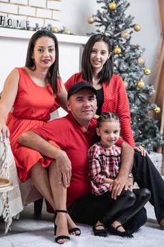 Hermosa familia en su casa posando para la foto navideña con ropa roja y adornos blancos y dorados