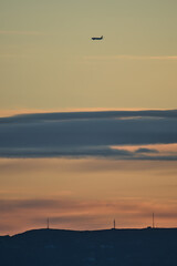 Fototapeta premium Beautiful early morning view of airplane passing above Howth seen from Blackrock, Dublin, Ireland before sunrise. Soft and selective focus