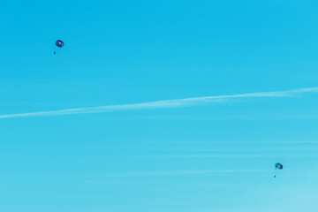 Extreme sports and exciting rest. Two tourists fly on a parashute in the blue sky background