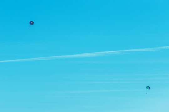 Extreme sports and exciting rest. Two tourists fly on a parashute in the blue sky background