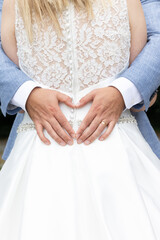 Groom holds his hands in the shape of a heart on the back of the bride in a white dress. High quality photo