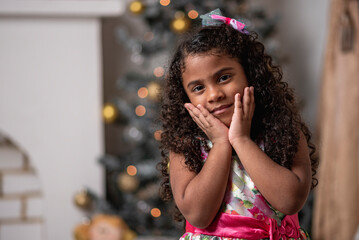 Hermosa niña afro caribeña disfrutando de la navidad con un árbol, adornos y regalos de fin de año