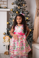 Hermosa niña afro caribeña disfrutando de la navidad con un árbol, adornos y regalos de fin de año