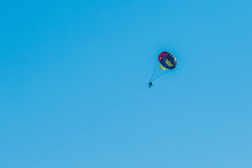 Extreme sports and exciting rest. Tourist fly on a parashute in the blue sky background