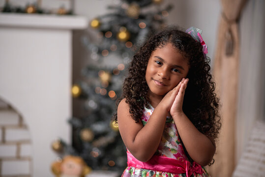 Hermosa niña afro caribeña disfrutando de la navidad con un árbol, adornos y regalos de fin de año