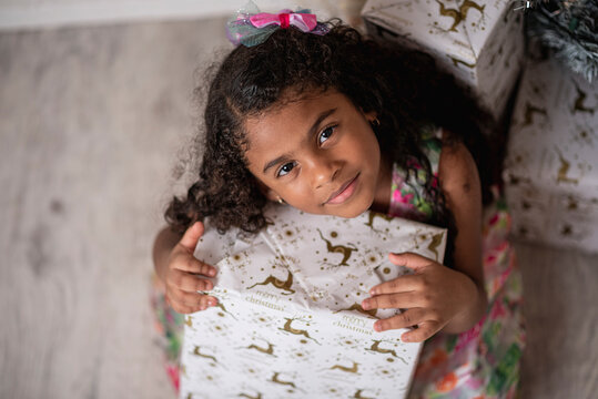 Vista superior de una hermosa niña afro caribeña disfrutando de la navidad con un árbol, adornos y regalos de fin de año