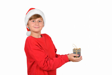 Happy smiling blond boy in Santa's hat and red pullover, holding a Christmas gift, waiting for holidays a new year dreamy expecting Christmas holidays, waiting gift and sales. Happy New Year banner