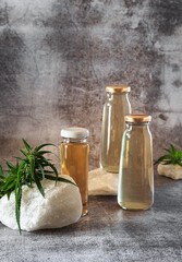 Three bottles of a drink with hemp extract and twigs of a green plant on the stones. Balance. A drink that reduces stress and anxiety. A modern concept of healthy nutrition..