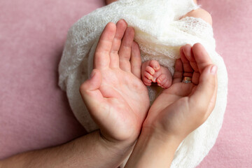 the feet of the newborn in the hands of the father