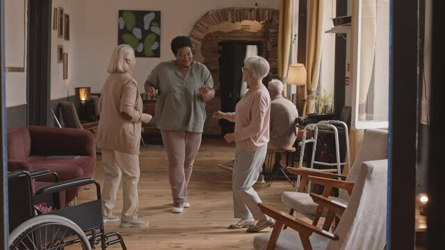 Slowmo shot of happy energetic old ladies having fun while dancing to music in cozy nursing home