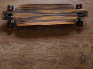Top view to the part of brown longboard with brown rubber wheels and logo ARBOR. Dark mood.